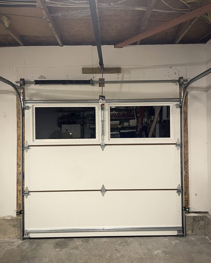 A garage door in its track from inside, with exposed framing overhead