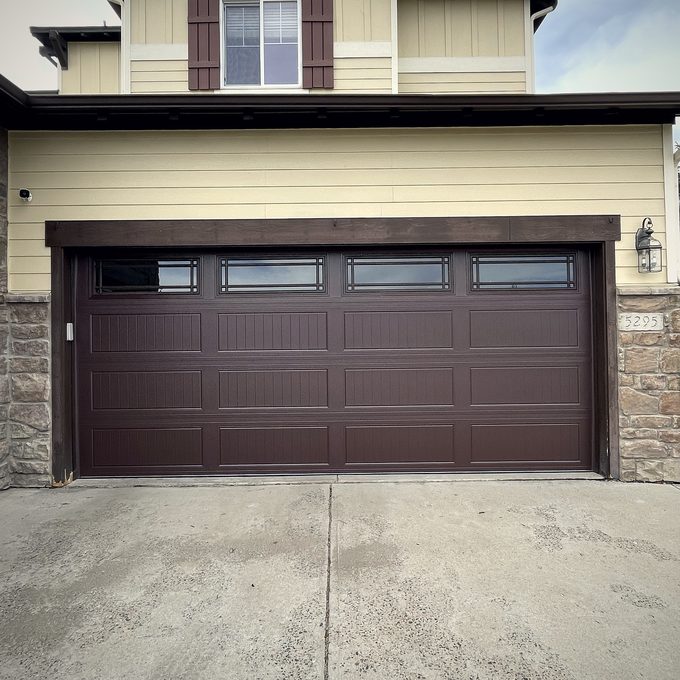 A dark brown raised panel garage door on a two storey house