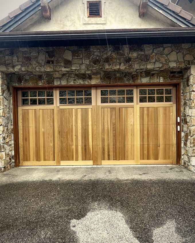 A light cedar carriage door set into a stone faced house