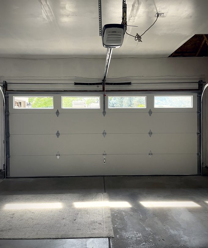 A pale sectional garage door seen from the back of the garage