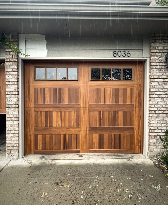 A mahogany garage door with window lights in the rain