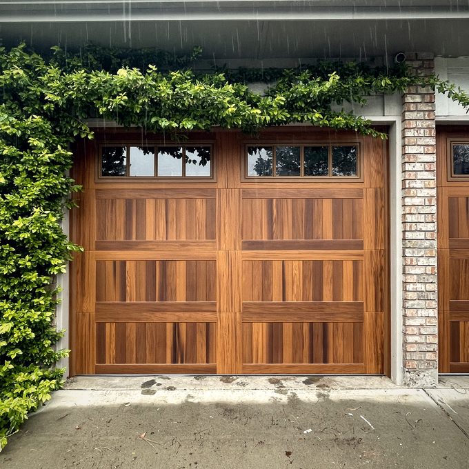 A mahogany garage door framed by climbing vines
