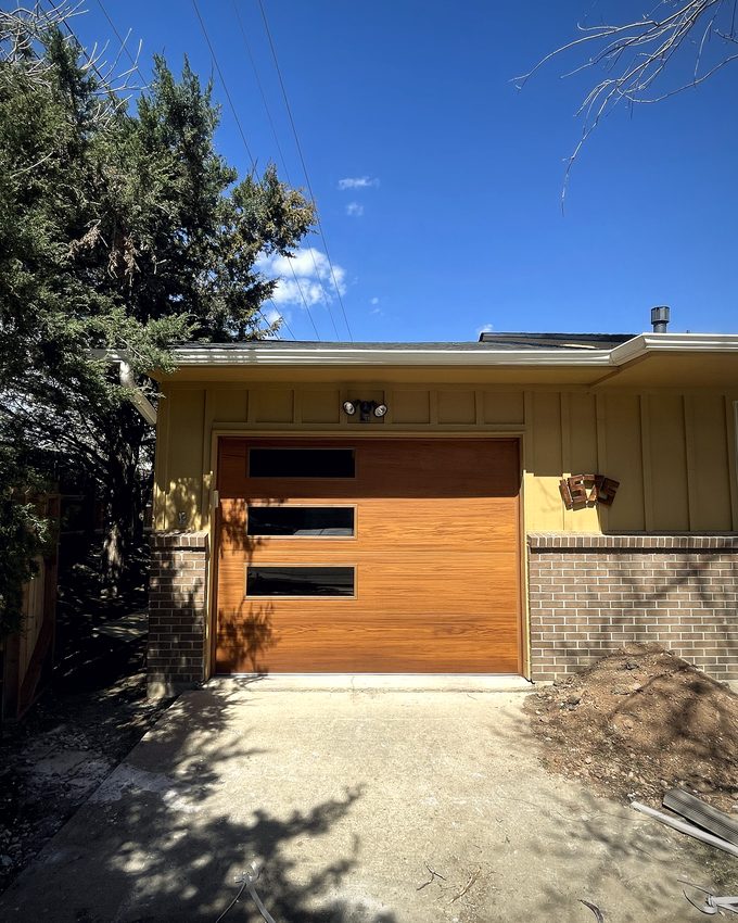 A modern flush wood garage door seen down the driveway