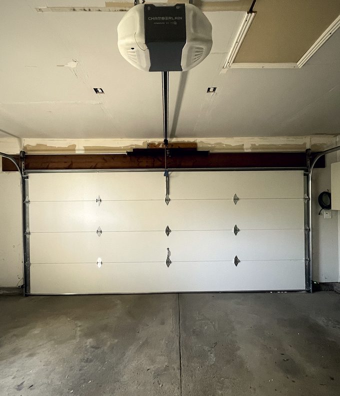 A ceiling mounted opener above a closed pale garage door