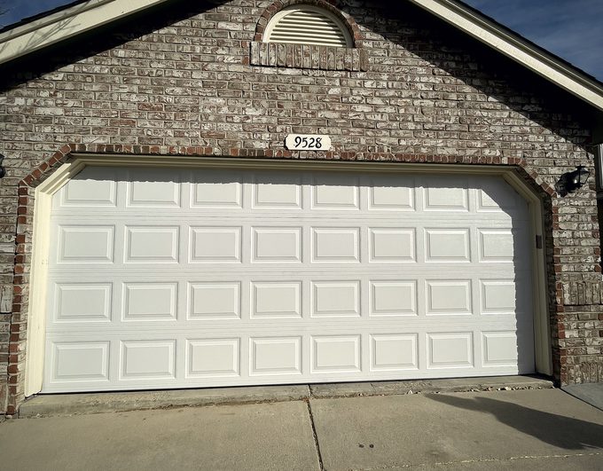 A white raised panel garage door under a brick arch